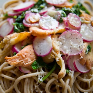 spaghetti topped with spinach, pink oyster mushrooms, radishes, cheese, and garlic olive oil sauce